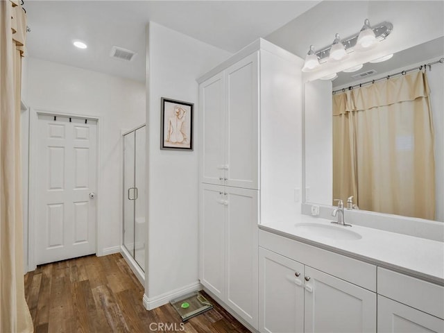 bathroom featuring a shower stall, visible vents, wood finished floors, and vanity