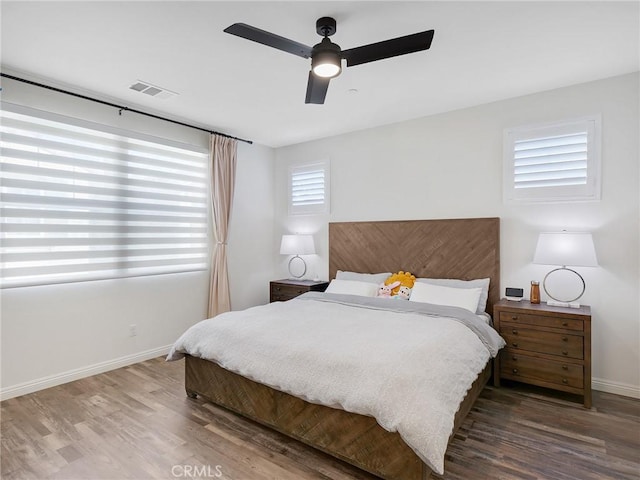 bedroom with ceiling fan, wood finished floors, visible vents, and baseboards