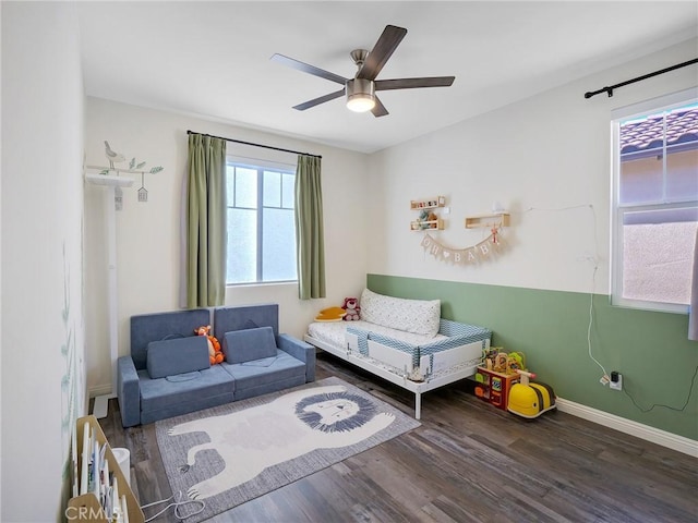 sitting room featuring dark wood-type flooring, ceiling fan, and baseboards