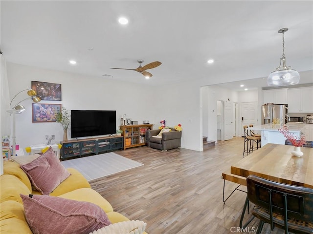 living area featuring light wood-style flooring, ceiling fan, and recessed lighting