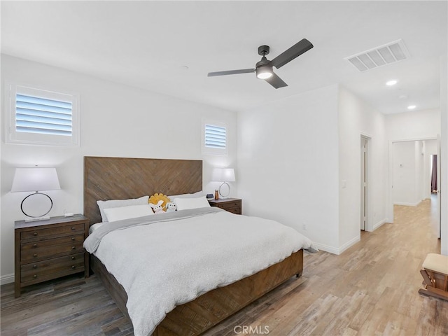 bedroom featuring light wood-style flooring, a ceiling fan, visible vents, and baseboards