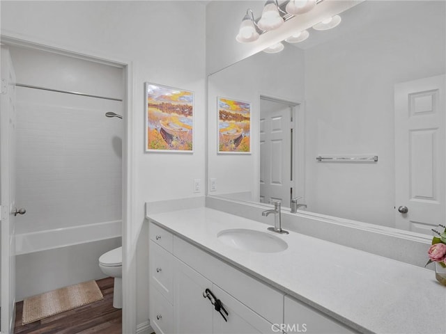 bathroom with toilet, washtub / shower combination, wood finished floors, and vanity