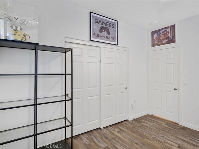 unfurnished bedroom featuring a closet, baseboards, and wood finished floors