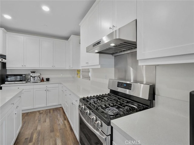 kitchen with range hood, light countertops, appliances with stainless steel finishes, white cabinets, and wood finished floors