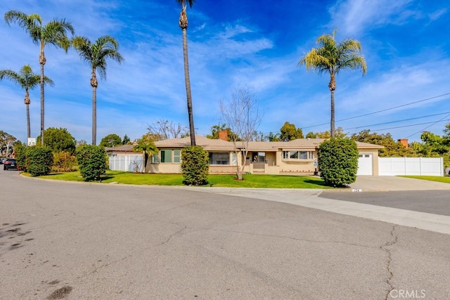 ranch-style house with a garage, driveway, a front lawn, and fence