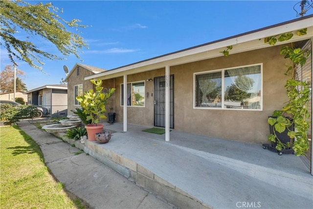 view of front facade featuring a patio, fence, and stucco siding