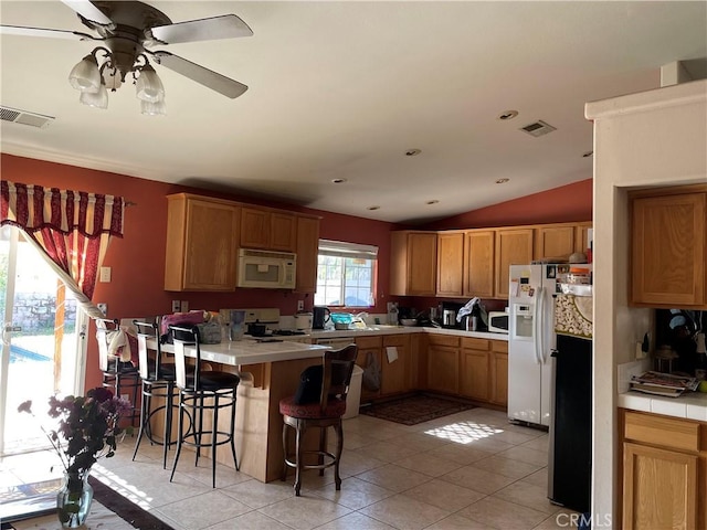 kitchen with brown cabinets, white appliances, light countertops, and visible vents