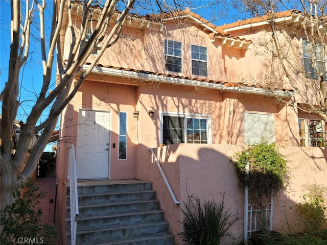 view of front of property with stucco siding, a tiled roof, and fence