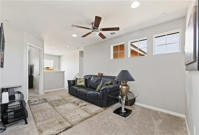 living area featuring plenty of natural light, baseboards, visible vents, and light colored carpet