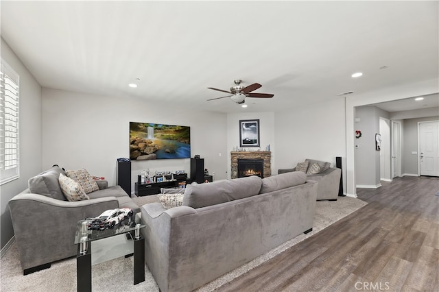 living room featuring recessed lighting, a ceiling fan, a stone fireplace, light wood-type flooring, and baseboards