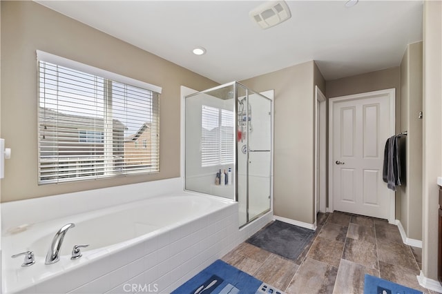 full bathroom with a garden tub, a shower stall, visible vents, and baseboards