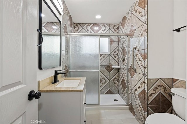 bathroom featuring tile walls, vanity, a shower stall, and toilet