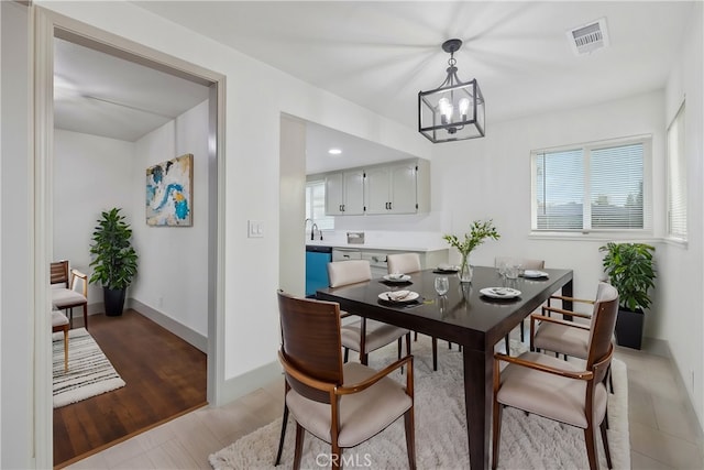 dining room with a notable chandelier, visible vents, light wood-style flooring, and baseboards