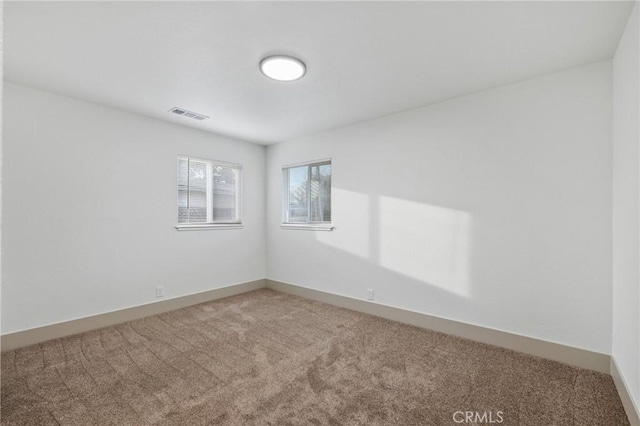 carpeted spare room with baseboards and visible vents