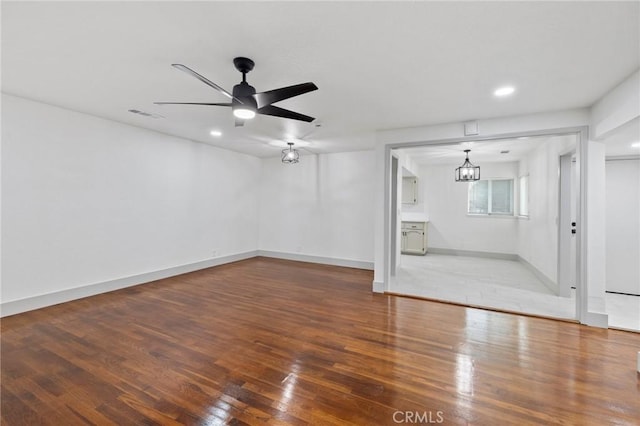 unfurnished living room featuring ceiling fan with notable chandelier, baseboards, wood finished floors, and visible vents