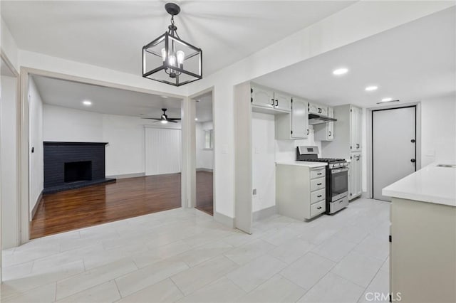 kitchen featuring open floor plan, light countertops, hanging light fixtures, and stainless steel range with gas cooktop