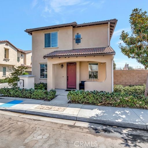 mediterranean / spanish home featuring a tile roof, fence, and stucco siding