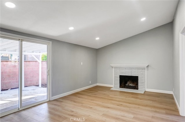 unfurnished living room featuring recessed lighting, baseboards, a fireplace, and light wood finished floors