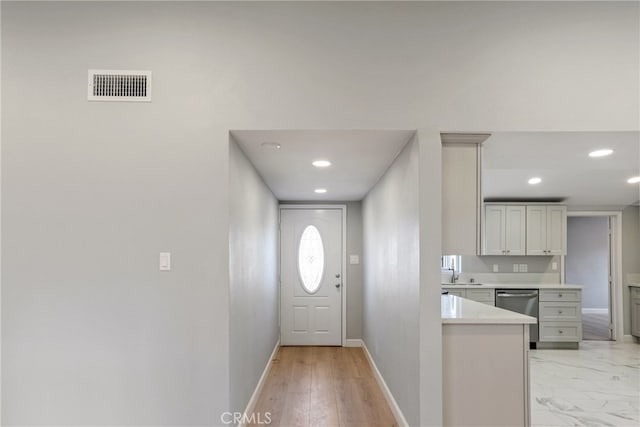 interior space featuring baseboards, visible vents, dishwasher, light countertops, and a sink