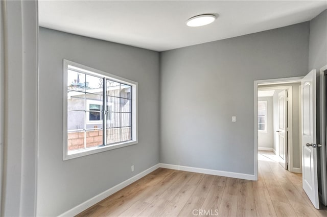 empty room with light wood-style flooring and baseboards