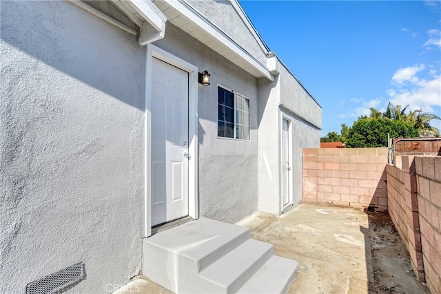 entrance to property with fence and stucco siding