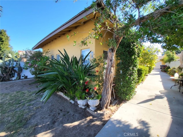 view of side of home featuring stucco siding and fence