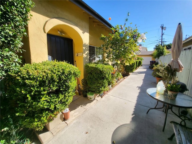 view of exterior entry featuring fence, stucco siding, and a patio area