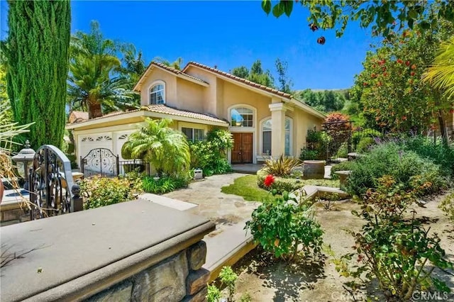 mediterranean / spanish-style house with a tile roof, an attached garage, and stucco siding