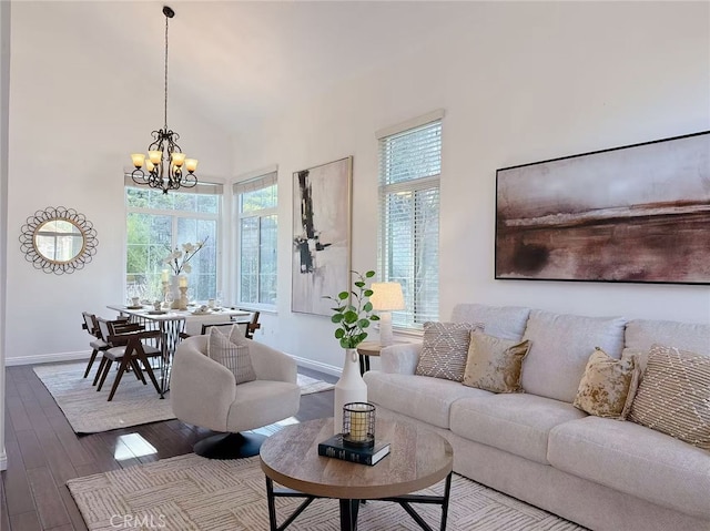 living area with a chandelier, wood finished floors, a towering ceiling, and baseboards