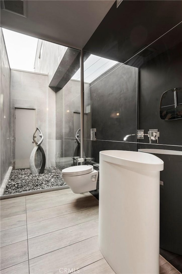 full bathroom featuring walk in shower, toilet, visible vents, vanity, and wood finished floors