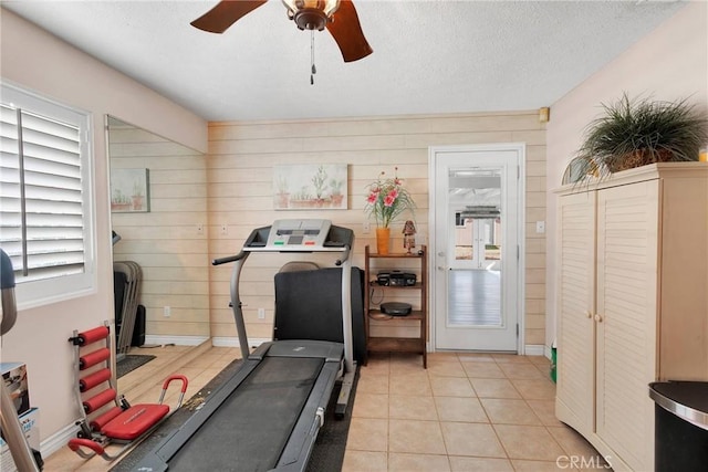 workout room with a textured ceiling, ceiling fan, and light tile patterned floors