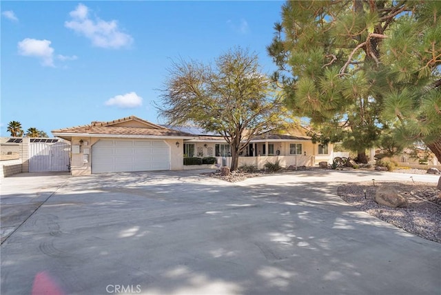 view of front of home with a garage, concrete driveway, a tile roof, and stucco siding