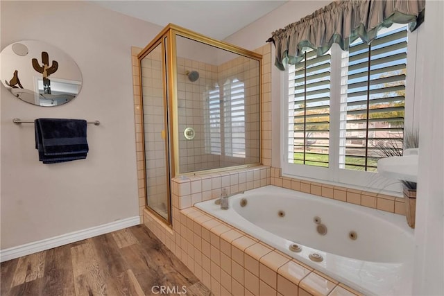 bathroom featuring a stall shower, a jetted tub, wood finished floors, and baseboards