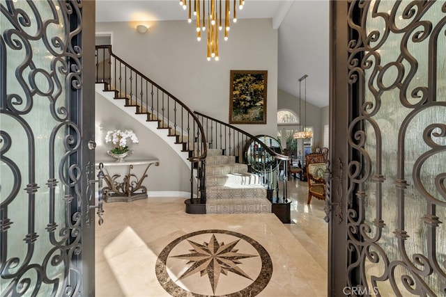 foyer with a high ceiling, stairs, baseboards, and a notable chandelier