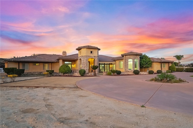 43840 E Vallejo Ave, Temecula, CA 92592 - mediterranean / spanish house featuring stone siding, stucco siding, curved driveway, a tiled roof, and a chimney
