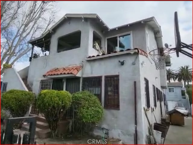 rear view of house with a tiled roof and stucco siding