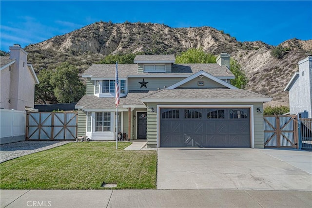 traditional-style home with an attached garage, fence, a mountain view, driveway, and a front yard