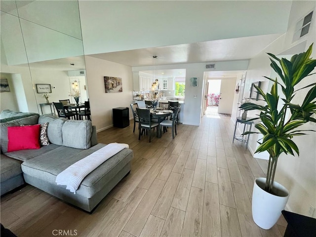 living area with a high ceiling, visible vents, and light wood finished floors