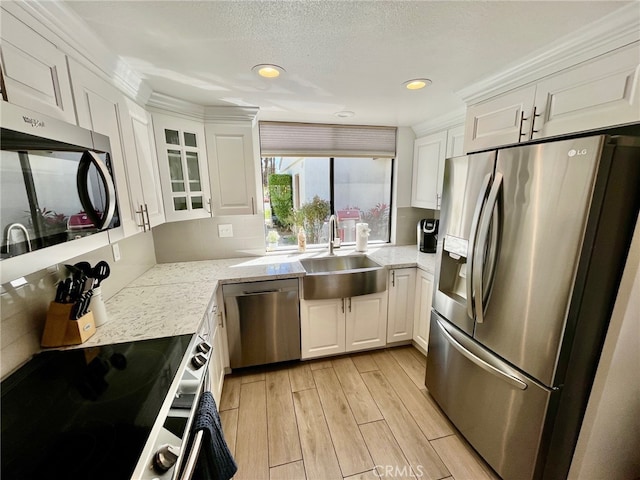 kitchen featuring appliances with stainless steel finishes, light wood-type flooring, a sink, and white cabinetry