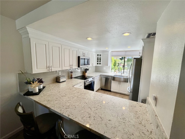 kitchen with visible vents, appliances with stainless steel finishes, white cabinets, a sink, and a textured ceiling