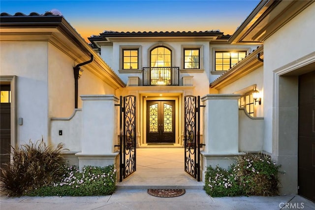 627 W Palm Dr, Arcadia, CA 91007 - exterior entry at dusk featuring a balcony, stucco siding, and a tile roof