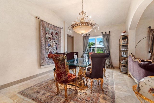 dining room featuring baseboards, lofted ceiling, and arched walkways