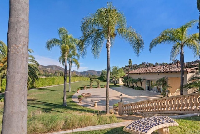 surrounding community with a mountain view, a yard, and a patio