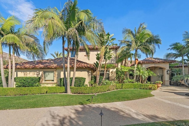 mediterranean / spanish-style house with concrete driveway, stucco siding, and a front yard