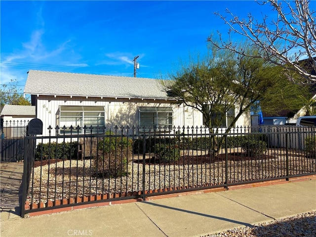 view of front of home with a fenced front yard and roof with shingles