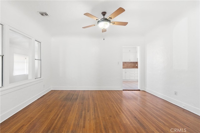 spare room featuring visible vents, baseboards, a ceiling fan, and wood finished floors