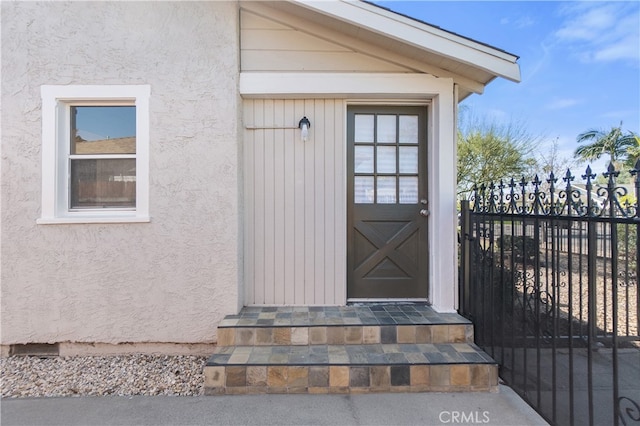 property entrance featuring stucco siding and fence