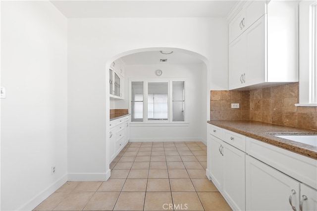 kitchen featuring decorative backsplash, baseboards, light tile patterned flooring, and white cabinetry