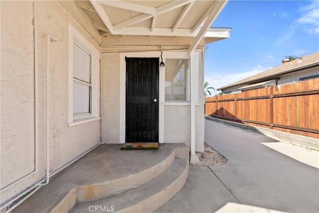 doorway to property with fence and stucco siding