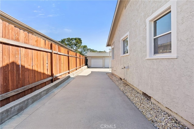 view of side of home featuring stucco siding, an outdoor structure, and fence